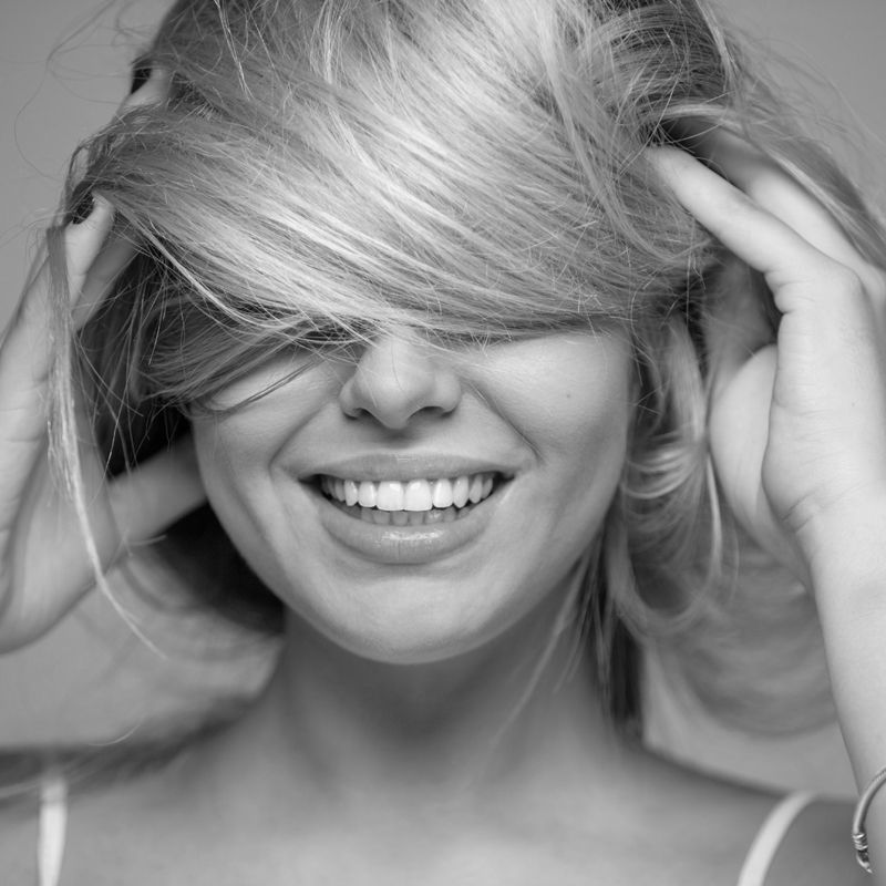 Retrato en blanco y negro de una chica con el pelo rubio con mechas por delante de la cara.