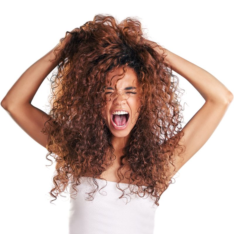 Una chica con el pelo rizado que está desesperada y se está agarrando la melena.