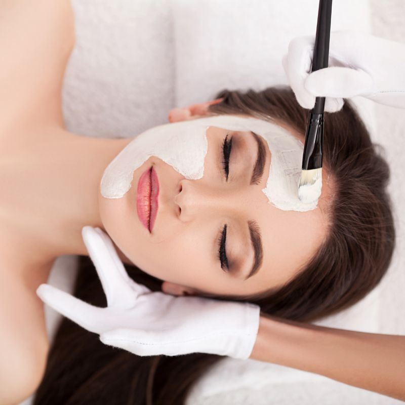 Imagen desde arriba de una chica que le están haciendo un tratamiento facial.